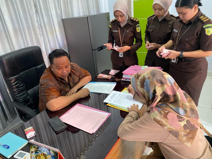 Ketgam: WORM mantan karyawan Bank Mandiri Taspen Kantor Cabang Pembantu (KCP) Baubau saat menandatangani berita acara penahanan dihadapan Kepala Seksi Pidana Khusus (Kasi Pidsus) Kejari Baubau, Iwan Gustiawan. Foto: Hariman